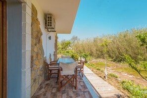 Un patio con tavolo e sedie, un muro in pietra e vista sul paesaggio circostante.
