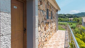 A stone building with a wooden door marked '18', a stone wall, and a metal railing overlooking a green landscape. - 'Mirage Arillas Studio Type C19' with Shared Pool & Wi-Fi (corfu)