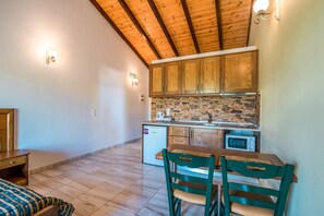 A compact kitchen with wooden cabinets, a stone backsplash, and a small refrigerator.