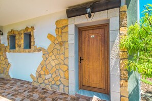 A stone wall with a wooden door marked '16' and a small window.