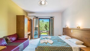 Une chambre avec un lit, un canapé, une armoire en bois et un balcon avec vue.