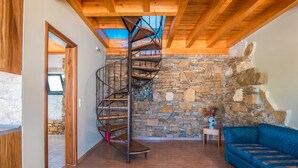 A spiral staircase in a room with stone walls, wooden beams, and a blue sofa. - Pet-Friendly Apartment 'Mirage Arillas Maisonette B' with Sea View, Shared Pool & Wi-Fi (corfu)