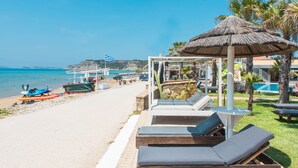 A beachside resort with lounge chairs, a thatched umbrella, and a pool.