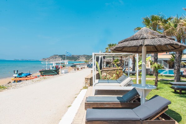 A beachside resort with lounge chairs, a thatched umbrella, and a pool.