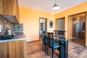 Una cocina moderna con salpicadero de piedra, armarios de madera y una mesa de comedor de vidrio con sillas.