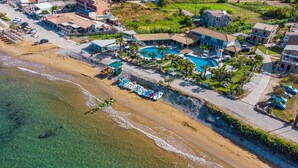 Eine Luftaufnahme eines Resorts mit Schwimmbad, Strand und Villen.