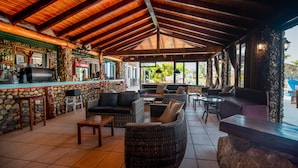 A covered outdoor seating area with stone walls, wicker furniture, and a bar counter. - 'Mirage Arillas Studio Type B15' with Sea View, Shared Pool & Wi-Fi (corfu)