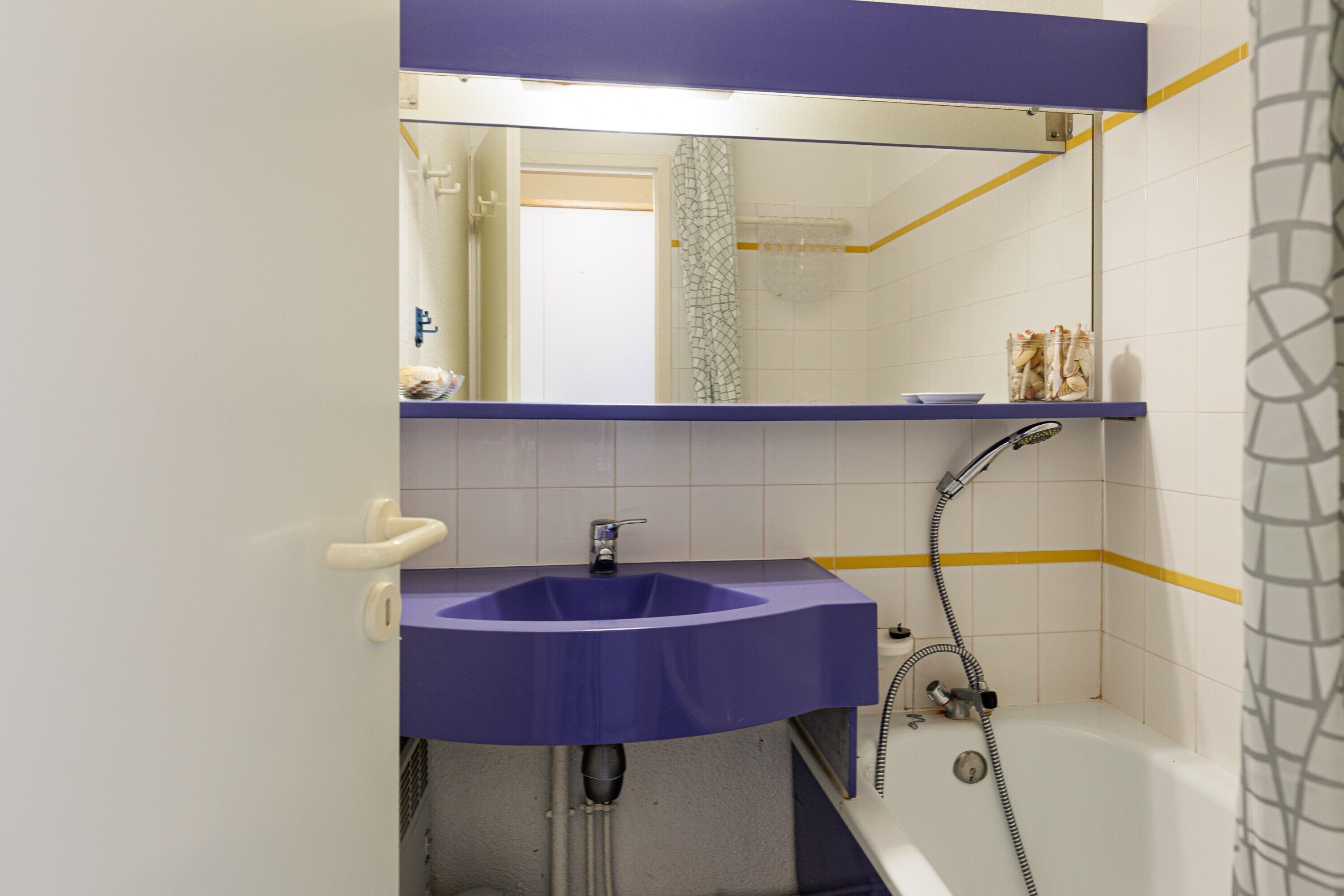 Une salle de bain avec un lavabo violet, une douche et une baignoire.