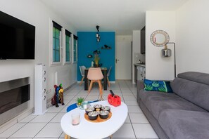 Ein Wohnzimmer mit grauem Sofa, einem weißen Couchtisch mit dekorativen Schalen, einem an der Wand montierten Fernseher und einer blauen Akzentwand.