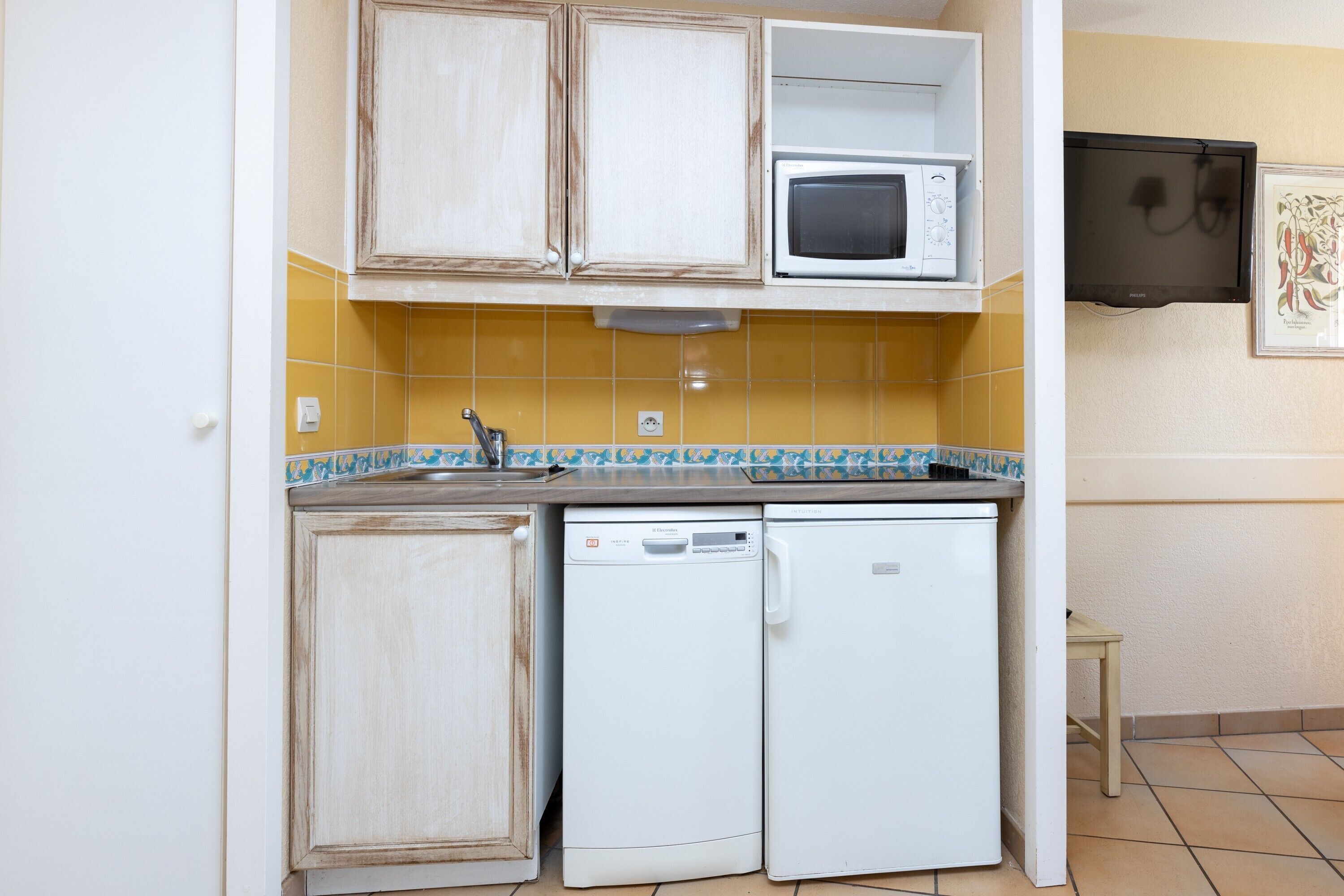 A compact kitchen with a microwave, dishwasher, and a small table.