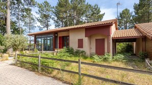 A building with a tiled roof, a wooden fence, and a paved walkway. - Villa with Stunning Views, Terrace and Garden (Moliets-et-Maa)