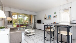 A modern kitchen with a dining area, a sofa, and a TV. - T3 with Heated Pool, Private Garden, and Golf Nearby – Moliets (Moliets-et-Maa)