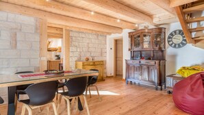 Een houten interieur met een eettafel, stoelen, een klok en een trap.