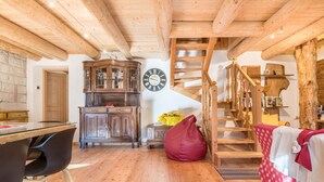 Een houten interieur met een trap, een klok en een eethoek.