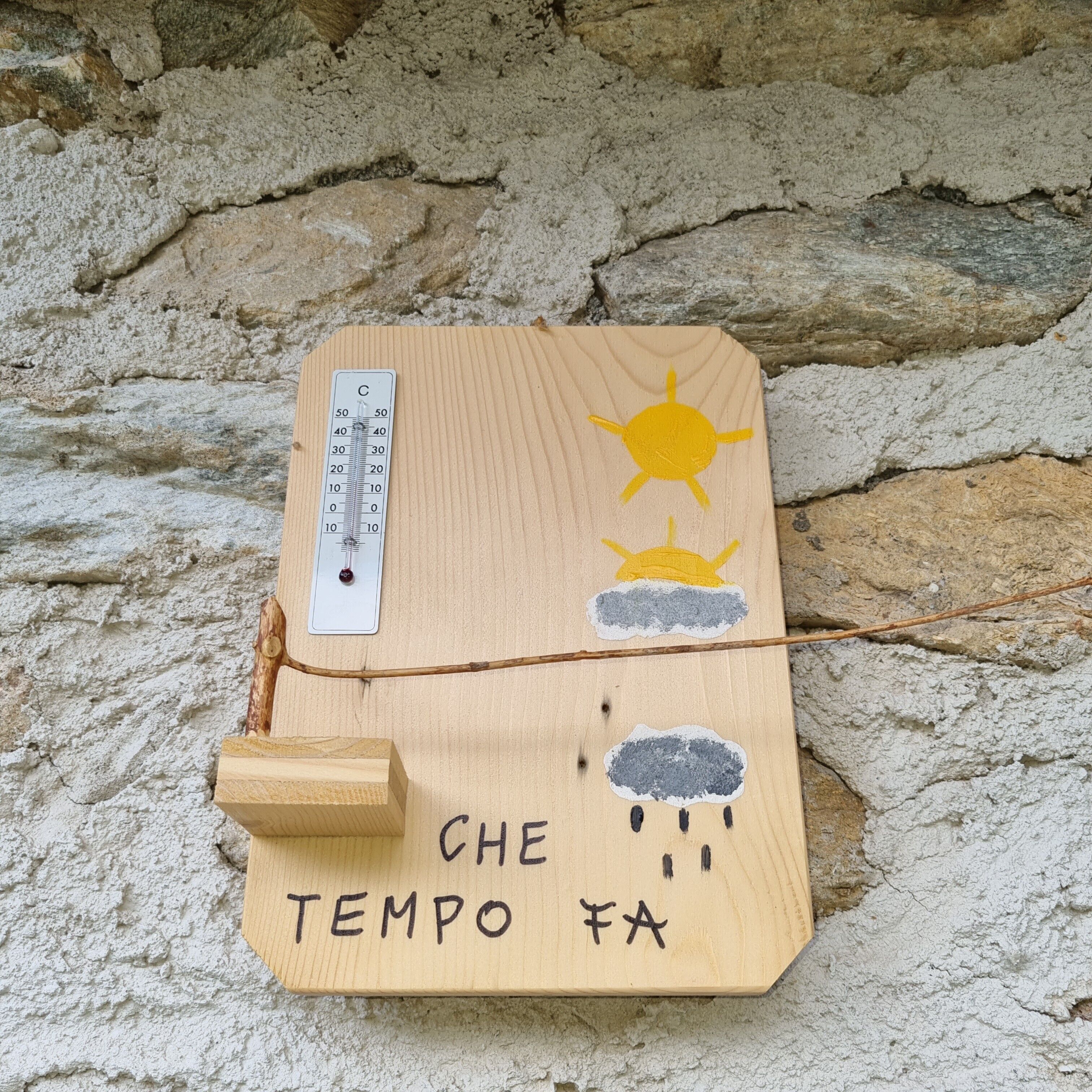 Una tavoletta di legno con un termometro, un simbolo di sole e nuvole e il testo 'CHE TEMPO FA'.