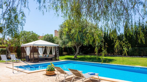 Une piscine avec des chaises longues, un belvédère et une pelouse bien entretenue.