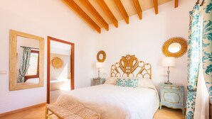 Une chambre à coucher comprenant un lit, un banc en bois, une table de chevet, un miroir et un objet décoratif fixé au mur.