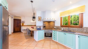 Une cuisine avec des meubles de couleur turquoise, un plan de travail en granit, un four encastré et une fenêtre donnant sur un paysage verdoyant.