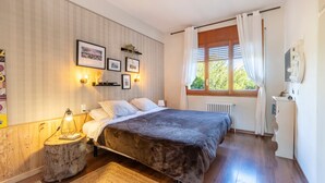 A bedroom with a large bed, a round wooden side table, a window with curtains, and wall-mounted lights. - Yoar Holiday Home with Mountain Views and Wi-Fi (Sant Llorenc de Morunys)