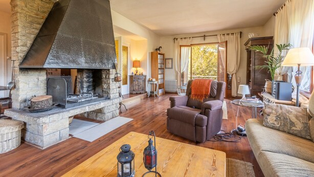 A cozy living room with a stone fireplace, comfortable seating, and a view of the outdoors. - Yoar Holiday Home with Mountain Views and Wi-Fi (Sant Llorenc de Morunys)