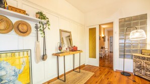 A hallway with a wooden floor, a woven rug, a table with a mirror, hats on the wall, and a lamp. - Yoar Holiday Home with Mountain Views and Wi-Fi (Sant Llorenc de Morunys)