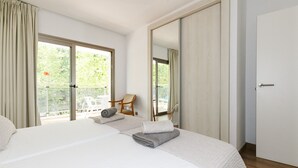 Hotellihuone, jossa on suuri sänky, puinen tuoli ja parveke, jolta on näkymä vehreään maisemaan.