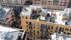 A high-rise residential building with multiple balconies, satellite dishes, and a central courtyard. - CAsa Ri al mare (Genova)