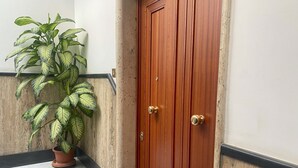 A wooden door with a brass handle, a potted plant with variegated leaves, and a marble staircase. - CAsa Ri al mare (Genova)