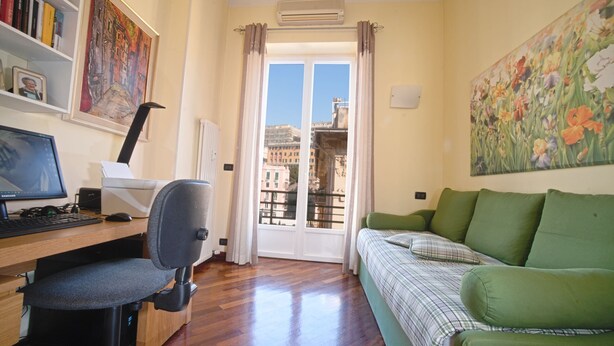 A room with a desk, chair, green sofa, and a view through a door. - CAsa Ri al mare (Genova)