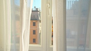 A view through a window with sheer curtains, revealing a building with a tiled roof and multiple windows. - CAsa Ri al mare (Genova)