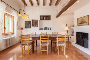 A dining area with a wooden table and chairs, a fireplace, and artwork on the walls.