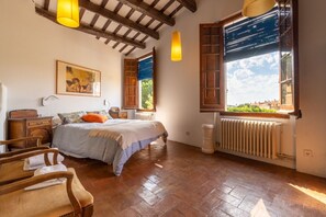 A bedroom with a bed, wooden furniture, a radiator, and a window with shutters.