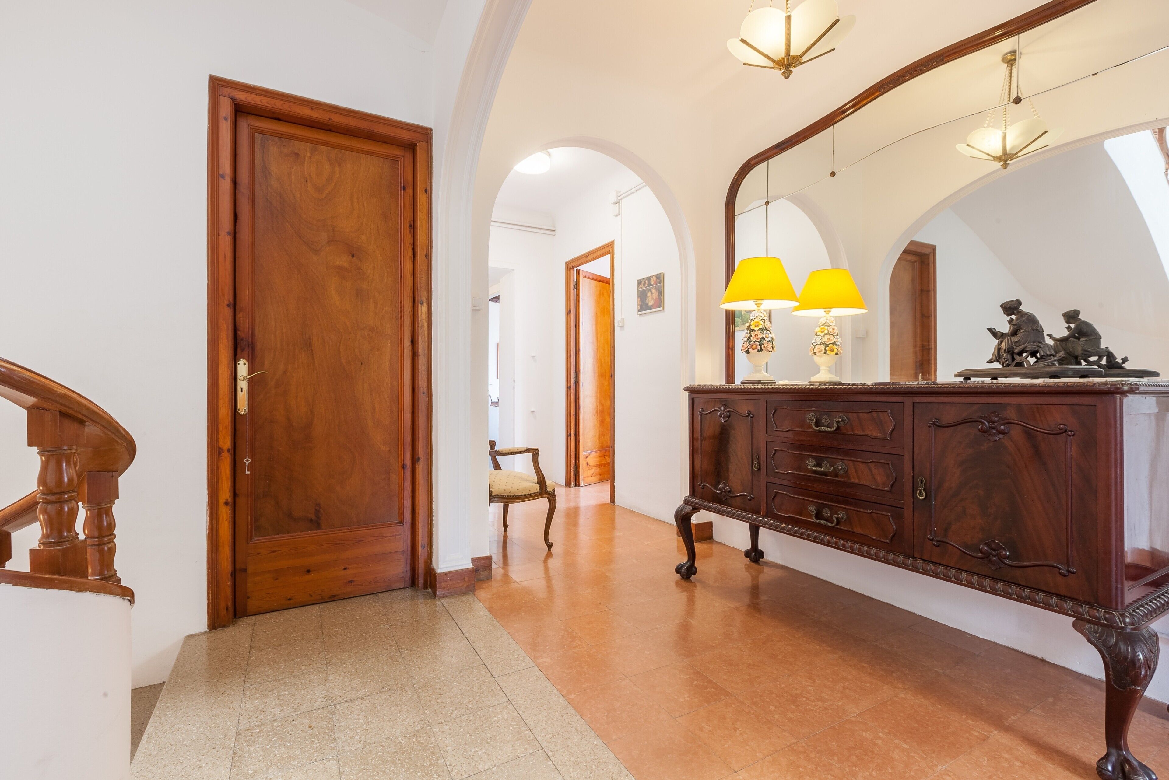 Ein Flur mit Holztür, einer Sitzbank, einem Schrank mit Lampen und einer gewölbten Decke.