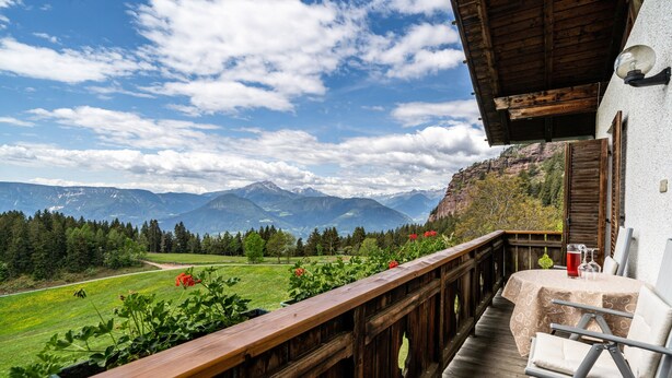 Un balcon doté d’une balustrade en bois, d’où l’on peut admirer un paysage montagneux.