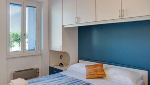 Un dormitorio con una cama, una ventana con persianas, un calentador y un armario.