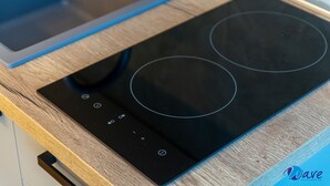 Una cocina de inducción negra con botones de control sobre una encimera de madera.