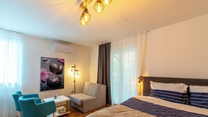 Una habitación de hotel con cama, sofá, sillón, escritorio y aire acondicionado instalado en la pared.