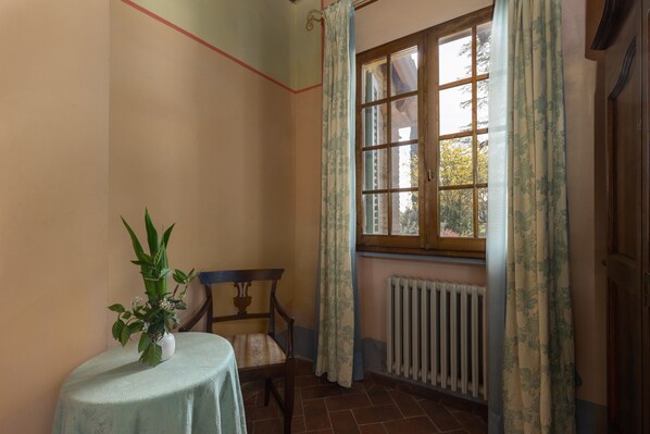 A room with a radiator, a window with curtains, a chair, and a table with a plant. - Villa 'La Limonaia' with Shared Pool, Private Terrace & Wi-Fi (Montespertoli)
