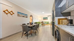 Una cocina moderna con horno empotrado, un comedor con mesa y sillas, y una sala de estar con sofá y mesa de centro.