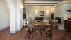 Un espace repas comprenant une table et des chaises en bois, une cheminée et un coin cuisine.