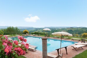 A swimming pool with lounge chairs and umbrellas, surrounded by greenery and hills. - Villa Il Frantoio with Shared Pool, Private Terrace & Wi-Fi (Montespertoli)