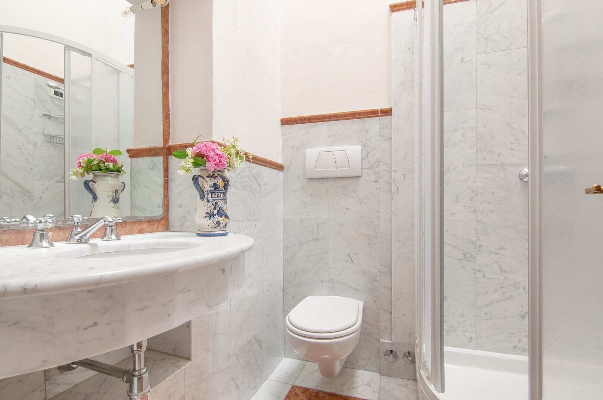Ein Badezimmer mit Marmorwaschbecken, Toilette und Duschbereich.