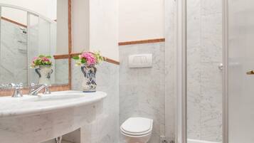 Ein Badezimmer mit Marmorwaschbecken, Toilette und Duschbereich.