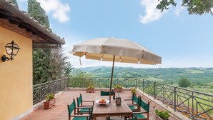 An outdoor patio with a table, chairs, and a large umbrella. - Apartment 'La Terrazza' with Shared Pool, Private Terrace & Wi-Fi (Montespertoli)