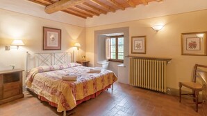 A bedroom with a bed, bedside tables, a radiator, a window, and framed pictures on the walls. - Apartment 'La Torre' with Shared Pool, Private Terrace & Wi-Fi (Montespertoli)