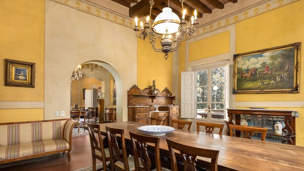 A dining room with a large wooden table, chairs, a chandelier, and a painting on the wall. - Villa Milani with Shared Pool, Private Terrace & Wi-Fi (Montespertoli)