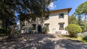 A building with a large entrance, potted plants, and a statue in the foreground. - Villa Milani with Shared Pool, Private Terrace & Wi-Fi (Montespertoli)