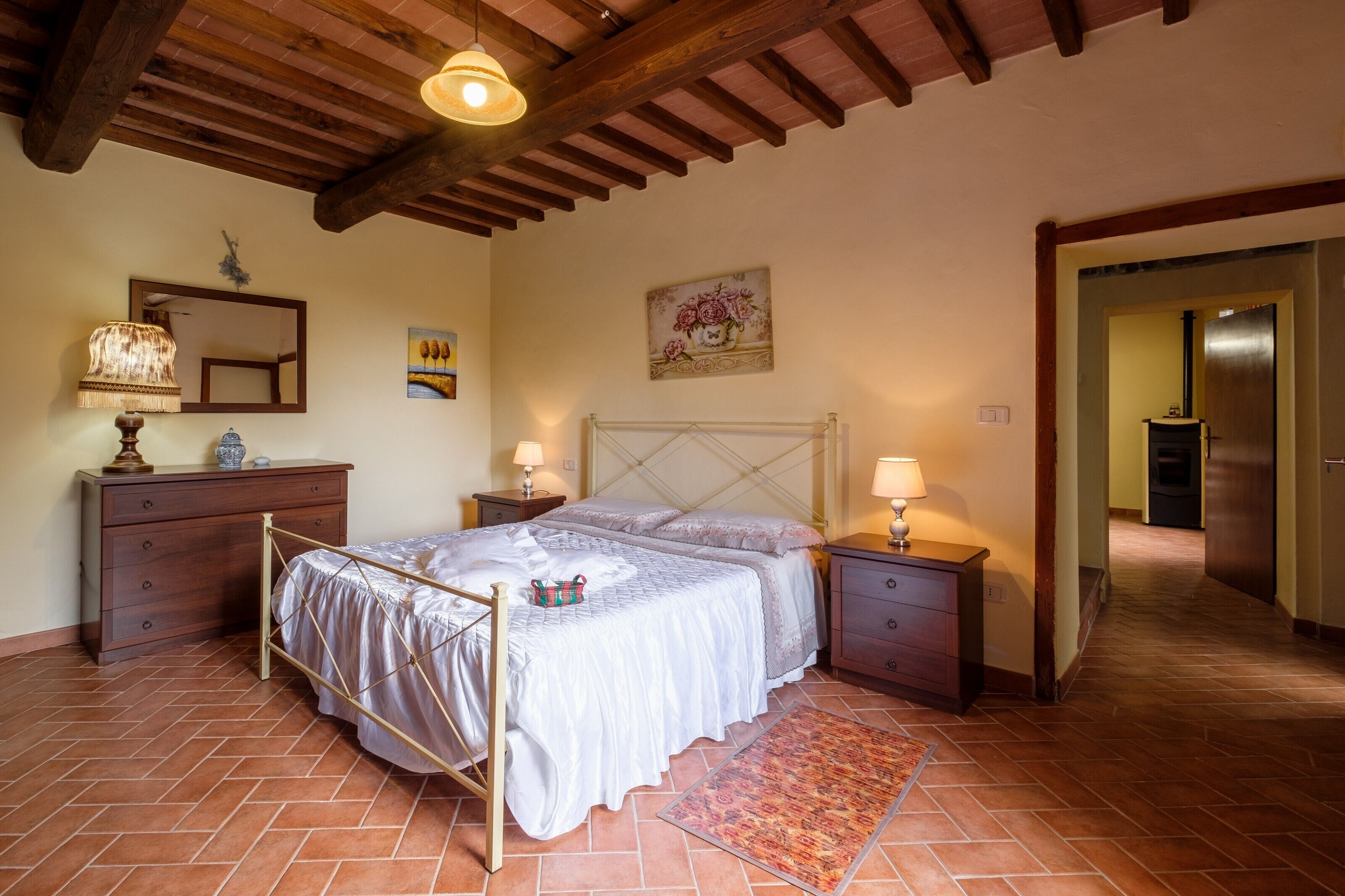 Une chambre à coucher comprenant un lit, une tête de lit en bois, des tables de chevet, une commode, un miroir et un tableau accroché au mur.