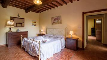 Une chambre à coucher comprenant un lit, une tête de lit en bois, des tables de chevet, une commode, un miroir et un tableau accroché au mur.