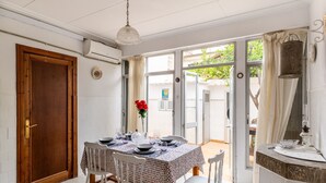 A dining area with a table set for four, a wooden door, and a view through the glass door. - Holiday Home 'Cas Llimoner' close to the Sea with Terrace & Wi-Fi (Palma)